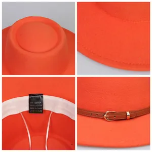Detail view of orange fedora featuring brown leather strap and golden metal buckle