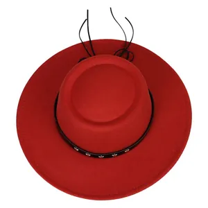 Detalle de sombrero de lana roja con banda de cuero negro y remaches de estrellas