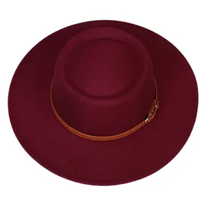Detail of burgundy flat top fedora hat with brown leather band and gold buckle strap