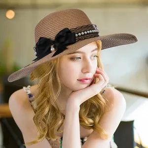 Elegant wide brim straw hat with black bow and pearl details worn by a model