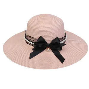 Pink wide brim straw hat with black bow, lace trim and pearl accents for beach wear