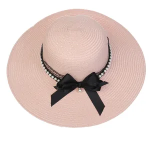 Macro view of woven straw hat featuring black lace, pearls and a satin bow detail