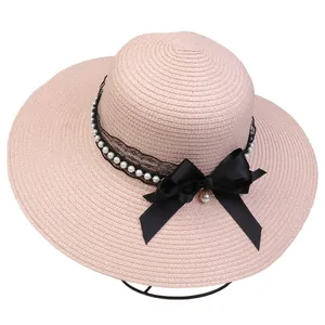 Detail of dusty pink wide brim straw hat with black lace, pearls and satin bow ribbon