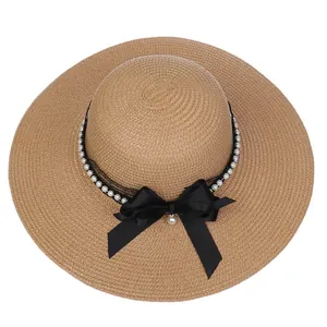 Detail of wide brim straw hat with black lace ribbon and pearl bow decoration
