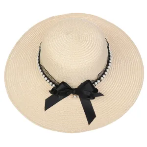 Detail of wide brim straw hat featuring black lace, white pearls and a satin bow knot