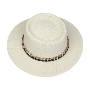 Detailansicht eines weißen Strohhutes mit schicker Goldkette und schwarzem Lederband von oben