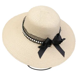 Close-up of elegant wide brim straw hat with pearl lace band and black satin bow accent