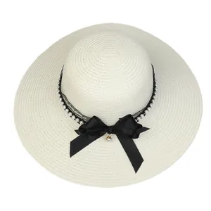 Detailed view of wide brim straw hat with elegant pearl trim and black lace bow