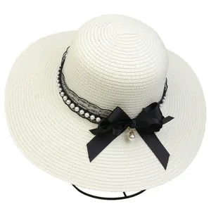 Close-up of beach straw hat featuring black bow, lace trim and elegant pearl details