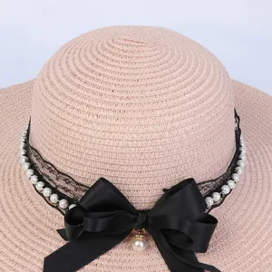 Detailed macro view of woven straw hat with black lace ribbon and pearl bow ornament