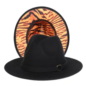 Detail of fedora hat showing wide brim with orange tiger print lining and metal buckle strap