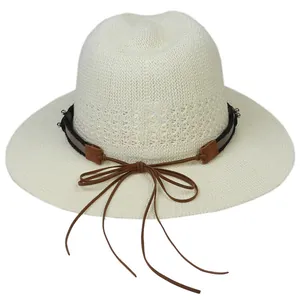 Ivory woven panama hat with brown leather band and fringe detail on white background