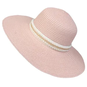 Detail of pink straw hat with lace ribbon, gold chain and white pearl accents