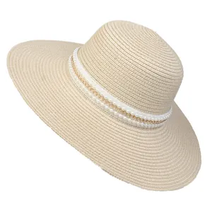 Detailed close-up of straw sun hat featuring elegant double pearl and gold chain trim