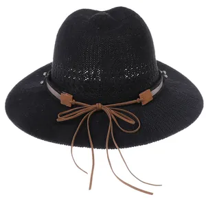 Close-up of black straw sun hat featuring breathable mesh crown and brown leather bow detail