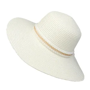 Detail of white straw hat with elegant double-row pearl and gold metal chain band