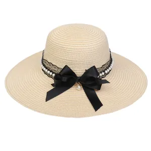 Elegant wide brim straw sun hat with pearls and large black satin bow for beach vacation