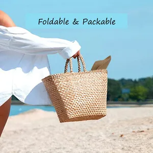 Foldable and packable brown straw sun hat being placed inside a woven beach tote bag