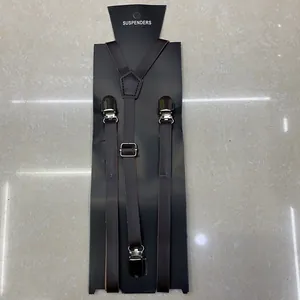 Detail view of dark brown leather suspenders with silver metal clips on display board
