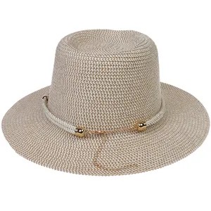 Detail of woven straw sun hat with white rope trim and decorative gold chain accent