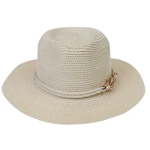 Detail of wide brim straw sun hat featuring decorative white ropes and rose gold chain link