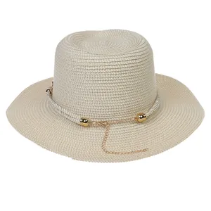Detail of straw boater hat featuring gold chain accents and white braided rope band