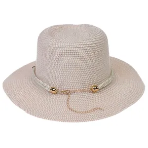 Close-up of woven straw sun hat texture with elegant gold chain and rope detail