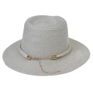 Detail of gray straw sun hat with woven white rope trim and gold chain ornament