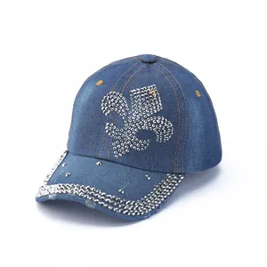 Detailed view of denim baseball cap with rhinestone fleur-de-lis and studded brim decor