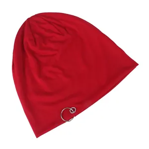 Detail of red knit beanie with interlocking silver rings on a clean white background