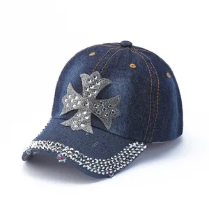 Detail of denim baseball cap featuring rhinestone cross and distressed brim edges