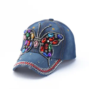 Detail of blue denim baseball cap featuring colorful rhinestone butterfly and studded brim