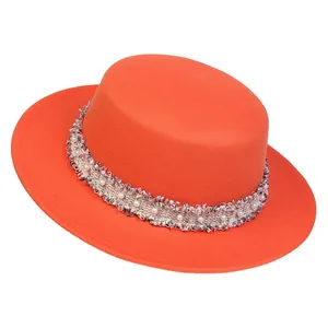 Detailansicht des orangen Wollhutes mit Perlenbesatz und gefransten Bandkanten