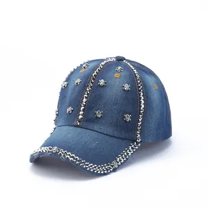 Detail of blue denim baseball cap featuring silver skull rivets and yellow stitching