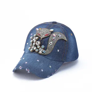 Detailed close-up of blue denim baseball cap with rhinestone fox patch and frayed brim