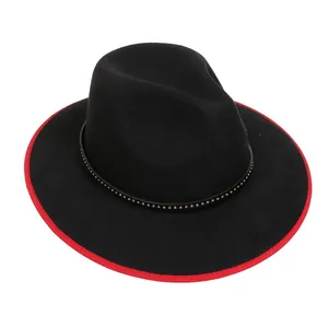 Dettaglio cappello in feltro nero con bordo rosso e fascia decorativa con borchie in metallo
