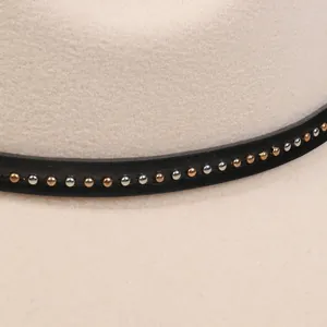 Dettaglio cappello in feltro di lana beige con fascia in pelle nera e rivetti metallici