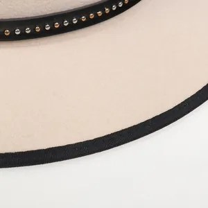 Dettaglio cappello in feltro di lana beige con fascia in pelle nera e borchie bull