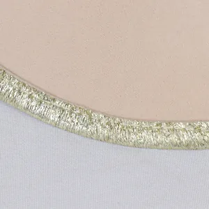Détail du tissu rose scintillant avec franges métalliques dorées et bordure soignée