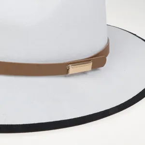 Dettaglio del cappello di lana bianco con cinturino in pelle marrone e fibbia dorata