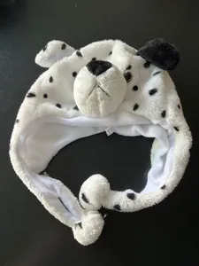 Detailed view of plush dalmatian hat with spotted faux fur and hanging pom-poms