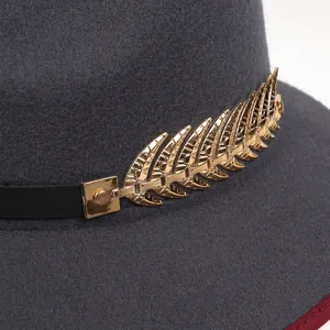 Dettaglio cappello in lana grigia con foglie in metallo dorato e tesa inferiore rossa
