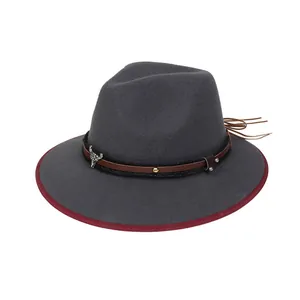 Dettaglio di cappello in feltro vintage con pendente a testa di toro e bordo bordeaux