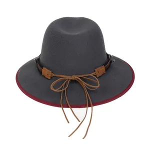 Dettaglio di un cappello fedora grigio scuro con bordo bordeaux e cinturino in pelle intrecciata