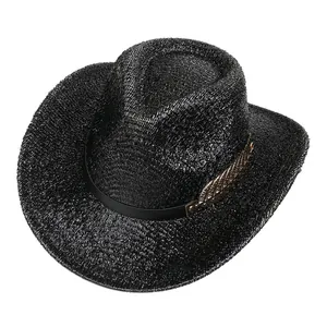 Détail d'un chapeau de cowboy noir en paille avec une plume dorée sur le ruban