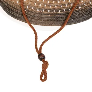 Detail of woven straw cowboy hat brim with brown windproof rope and wooden bead toggle