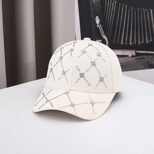 Détail de la casquette de baseball crème avec motifs en strass et clous en forme de fleurs
