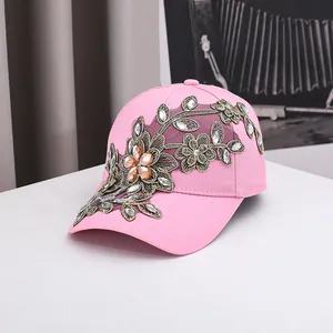 Détail de la casquette rose avec broderies florales dorées et accents de strass ambrés