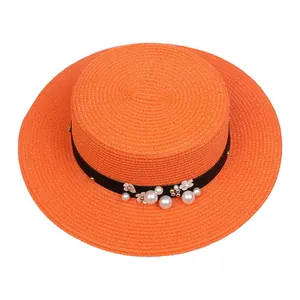 Detail of orange boater hat with black ribbon, white pearls and floral accents