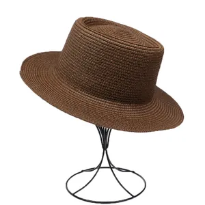 Detailed view of dark brown straw hat with fine weave texture on a black display stand